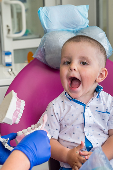 Toddler in the dental chair opening their mouth wide