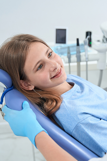 Teenage girl in the dental chair listening to her dentist